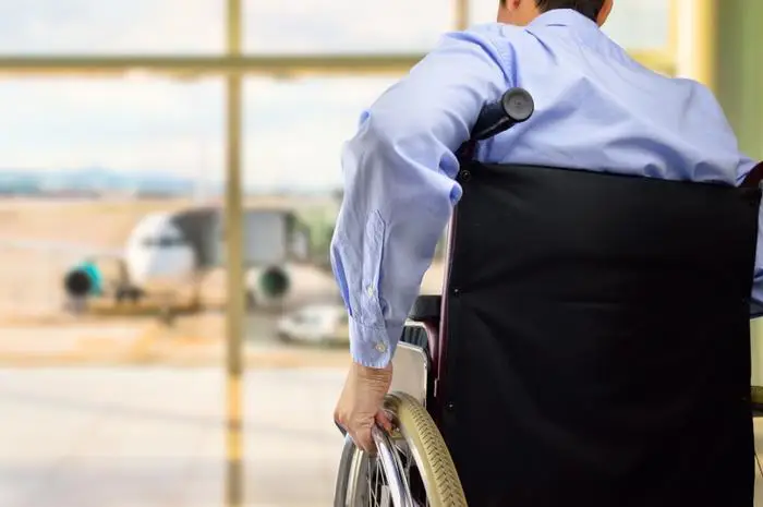 Wheelchar user looks out toward a plane at airport.