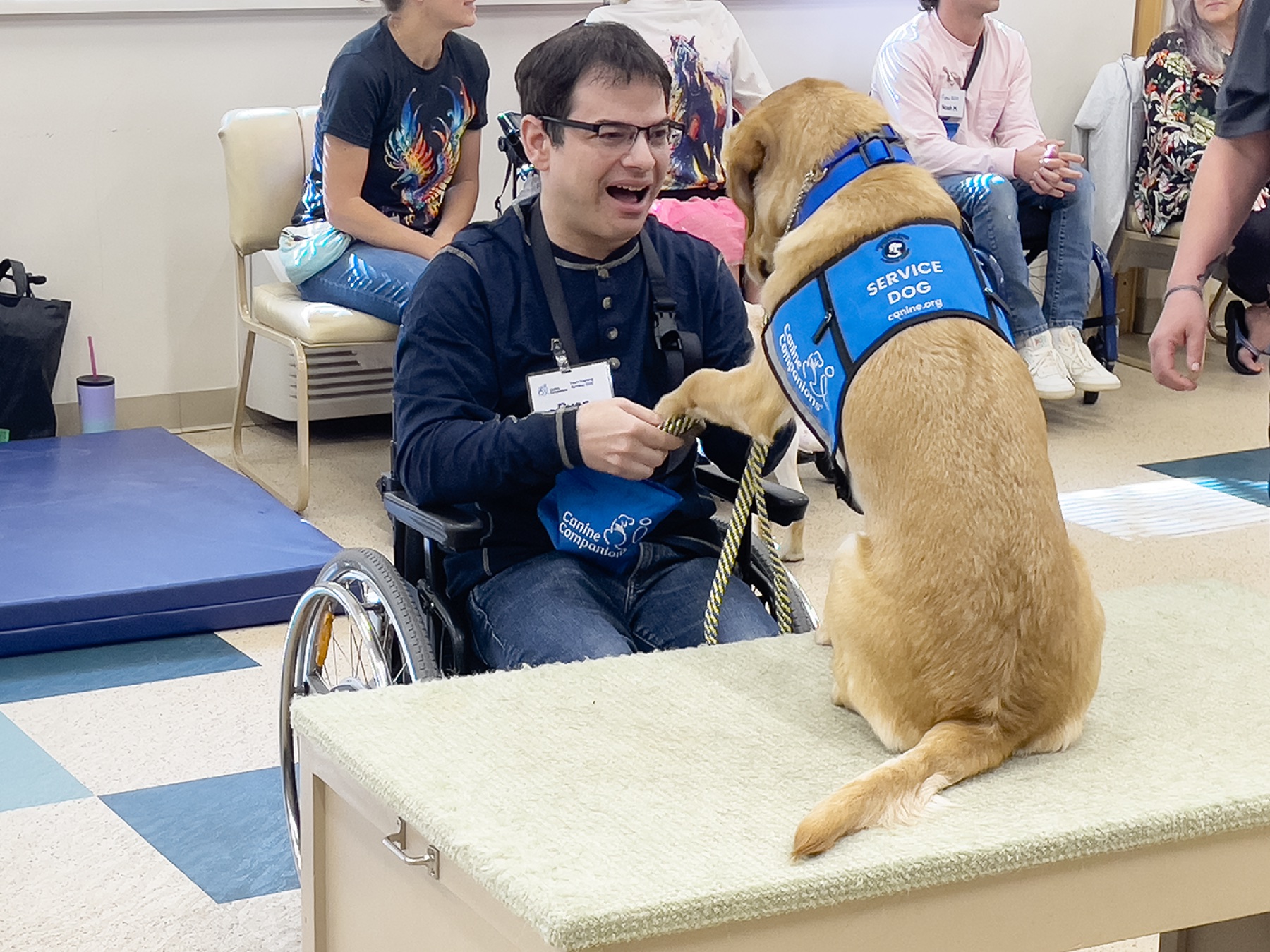 Ryan smiling as Lovey places a paw in his hand during service-dog training